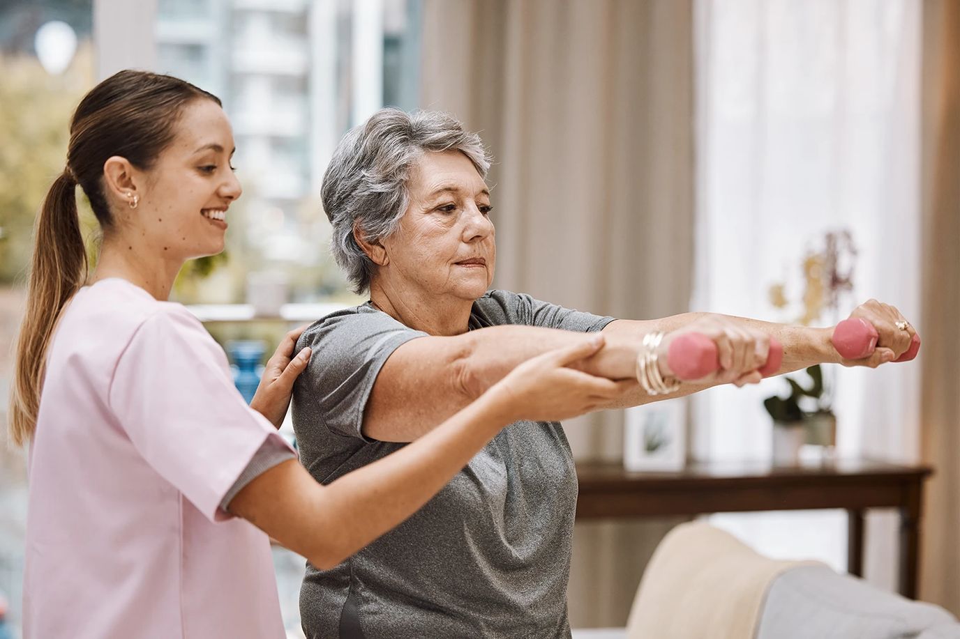 Staff assisting a resident with exercise using weights