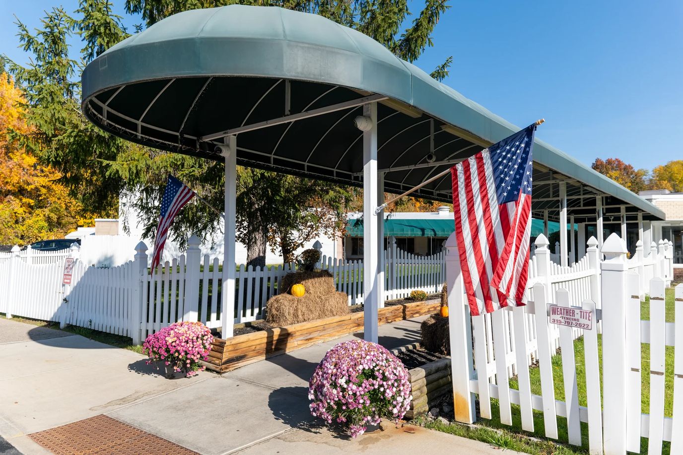 Entrance canopied area of a nursing home with flags and flowers