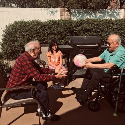 Two seniors and a child playing with a ball in the garden