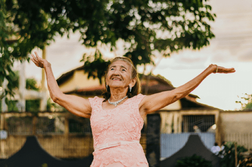 Elderly woman joyfully celebrating outdoors