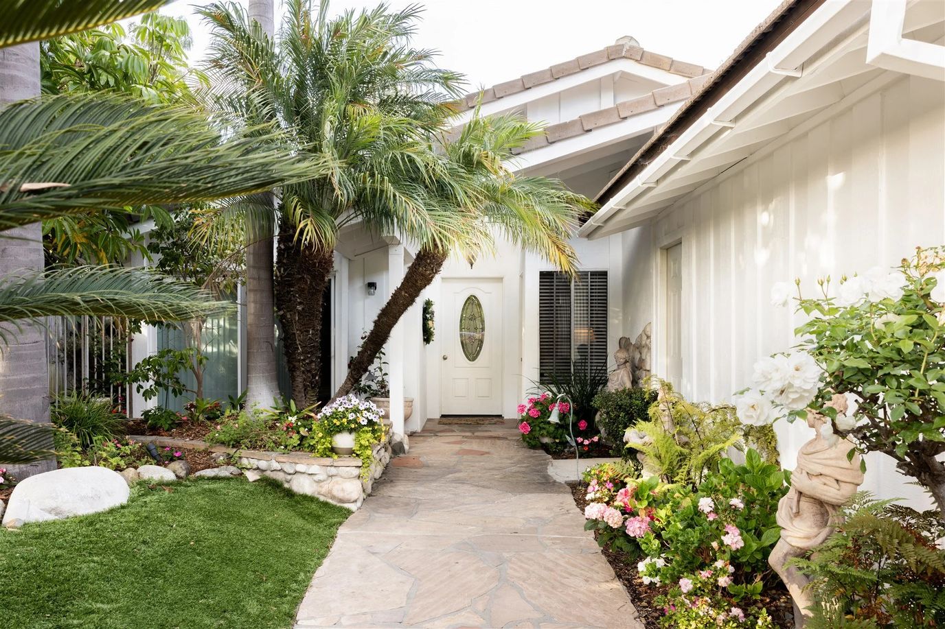 Pathway with lush plants leading to a front door