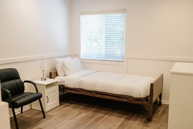 A bright, clean resident room with a bed and chair