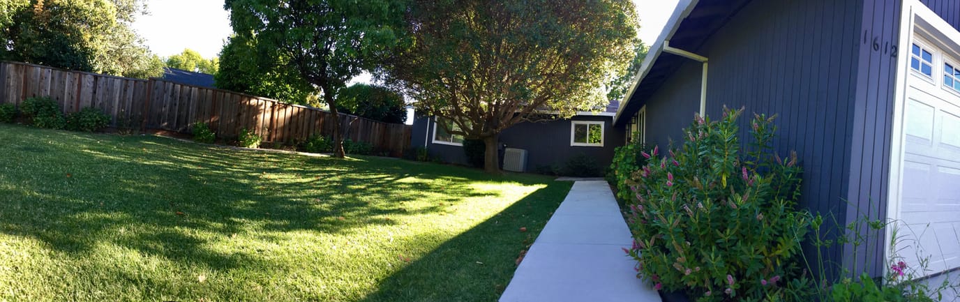 Exterior view of a care home with green lawn and trees