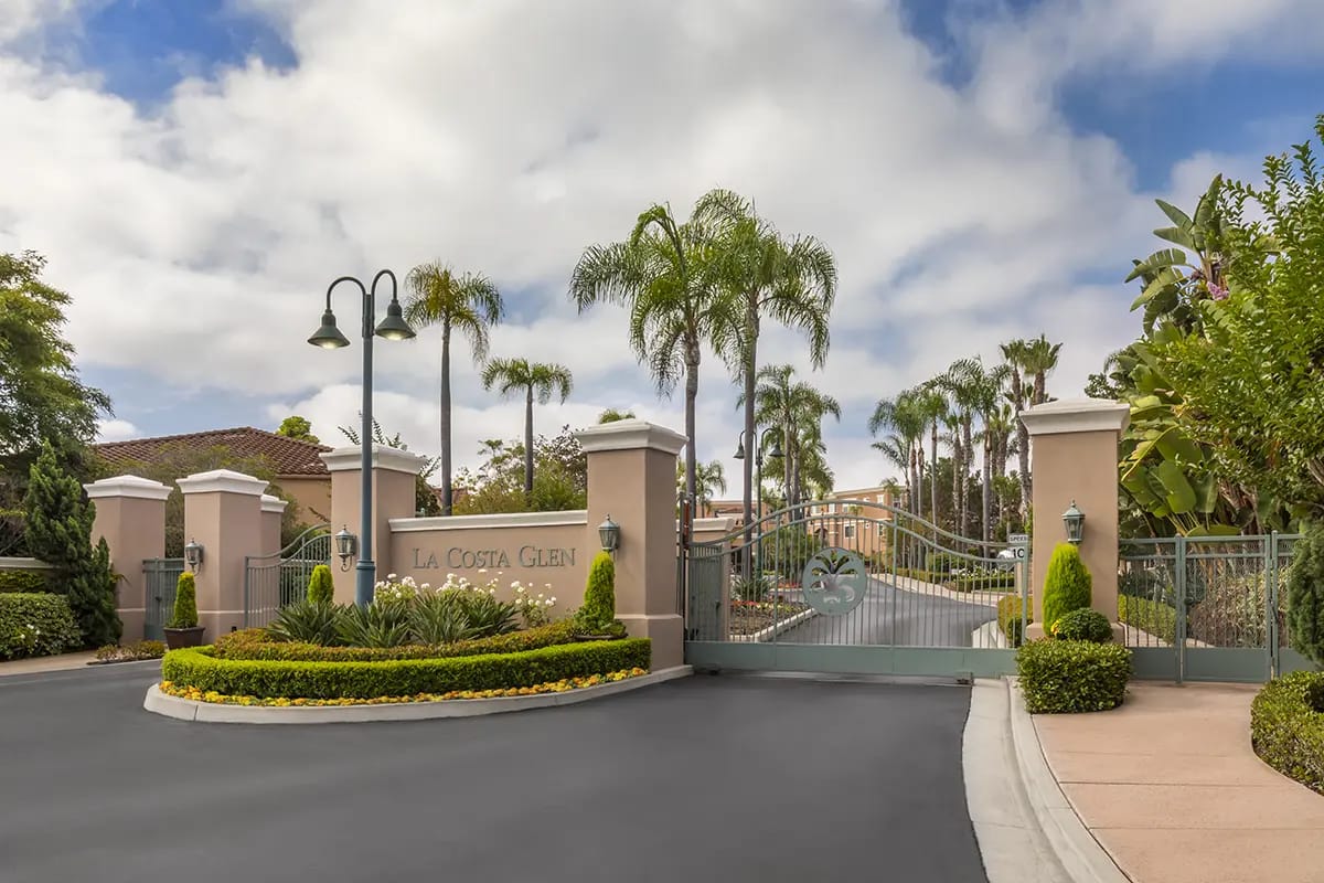 Entrance gate of La Costa Glen with palm trees and landscaping