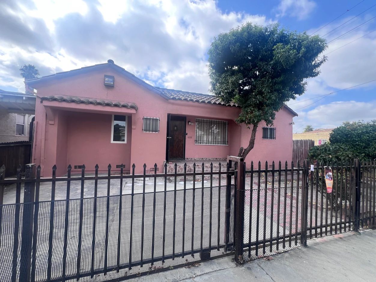 Exterior view of a pink house with fence