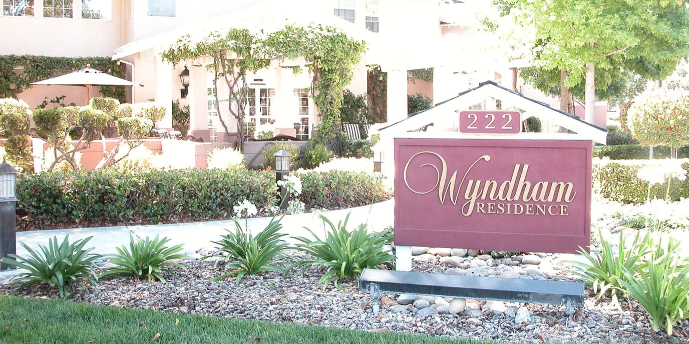 Exterior view of Wyndham Residence with a sign and landscaped garden