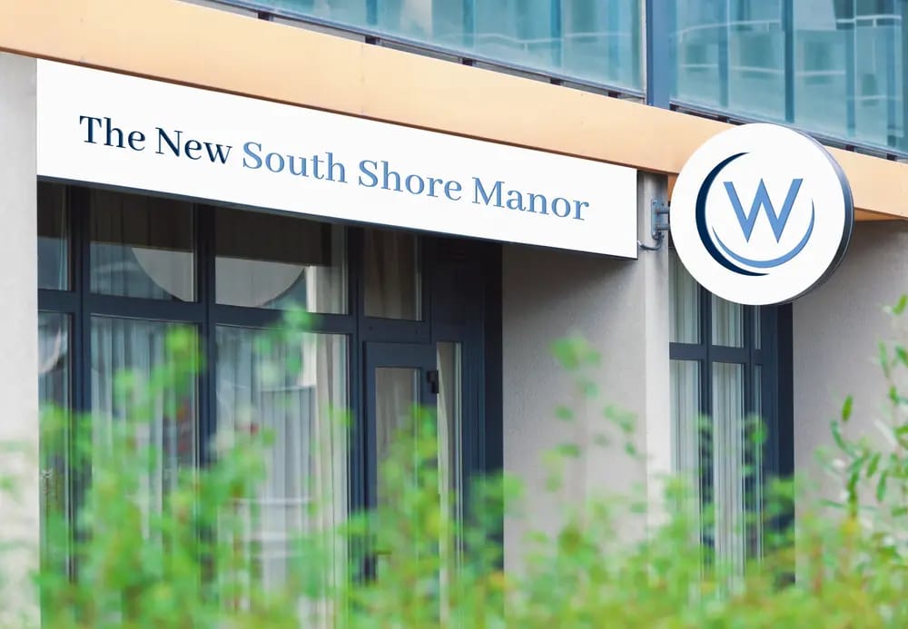 Exterior view of The New South Shore Manor building with logo.