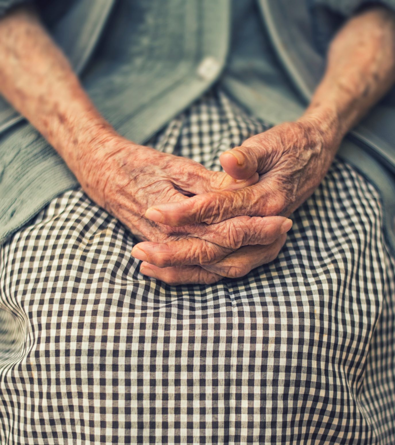 Close-up of elderly hands resting on a lap