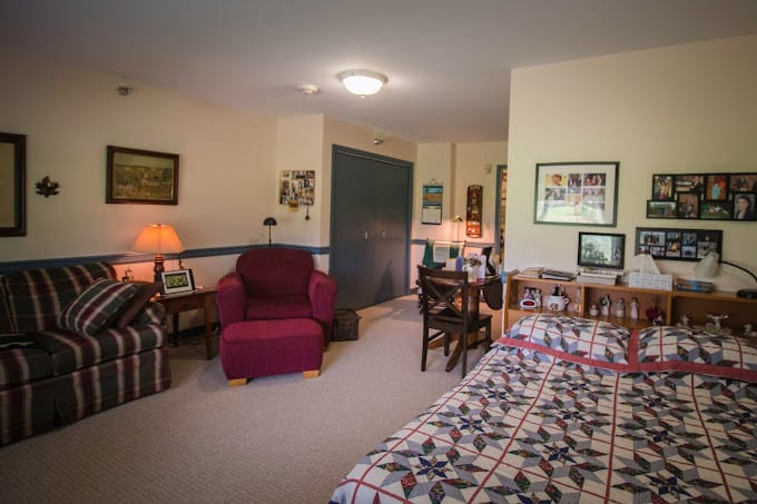 A cozy private resident room with a quilted bed