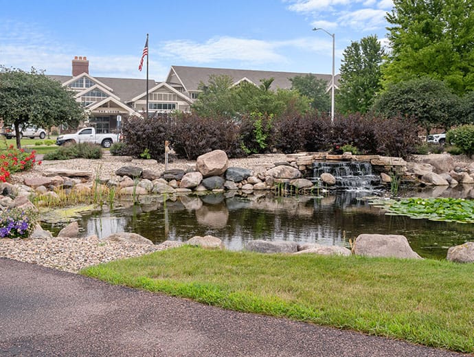 Beautiful landscaping with a pond and the facility in the background