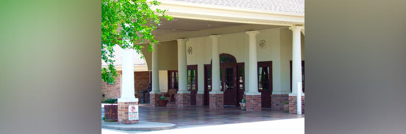 Entrance of Maison De Lafayette with pillars and greenery.