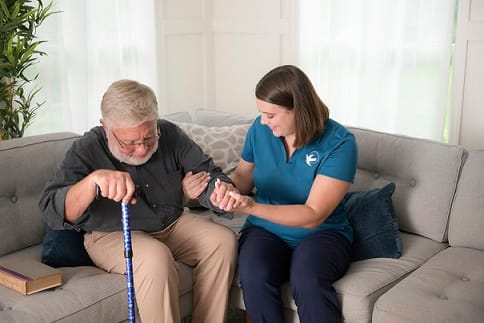 Caregiver assisting senior man on a couch