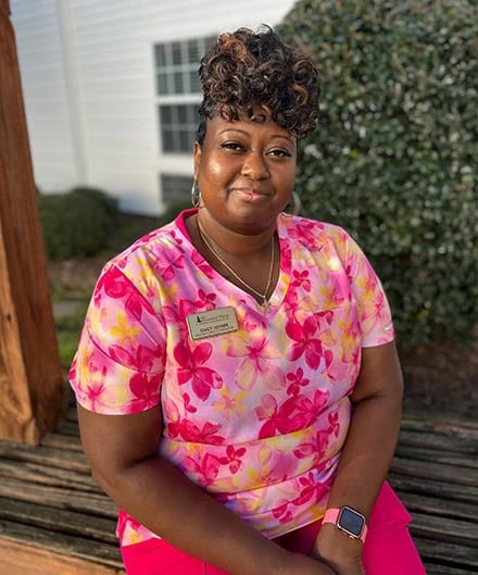A staff member smiling outdoors in a floral shirt