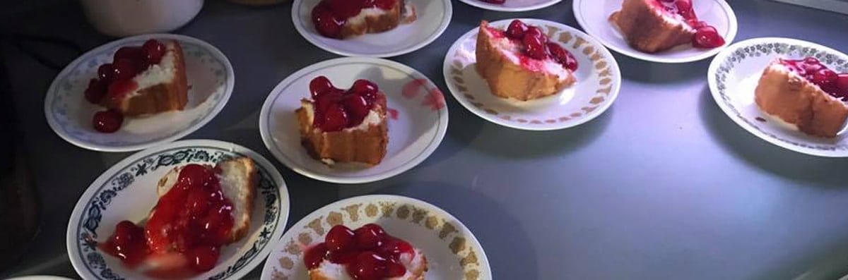Plates of cake with cherries on top.