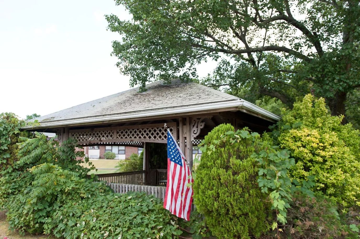 A gazebo surrounded by lush greenery and an American flag.
