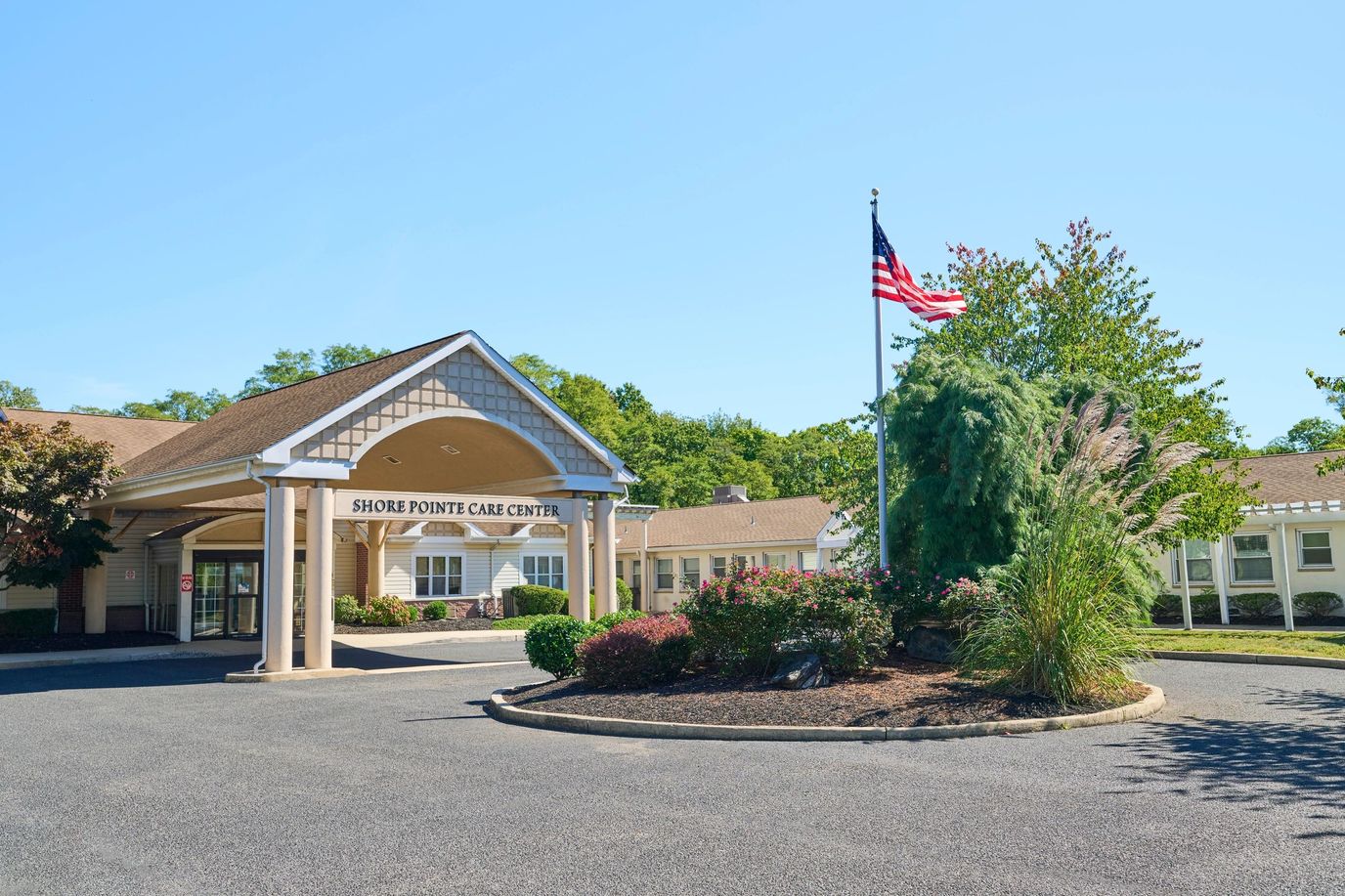 Entrance of Shore Pointe Care Center with flag and landscaping