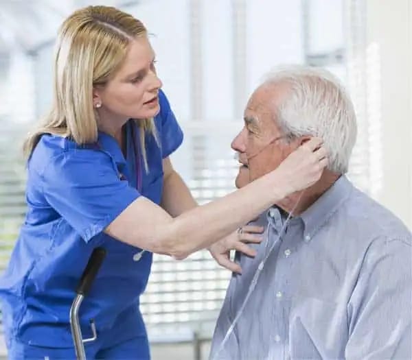 A caregiver assisting a senior man in an interior setting