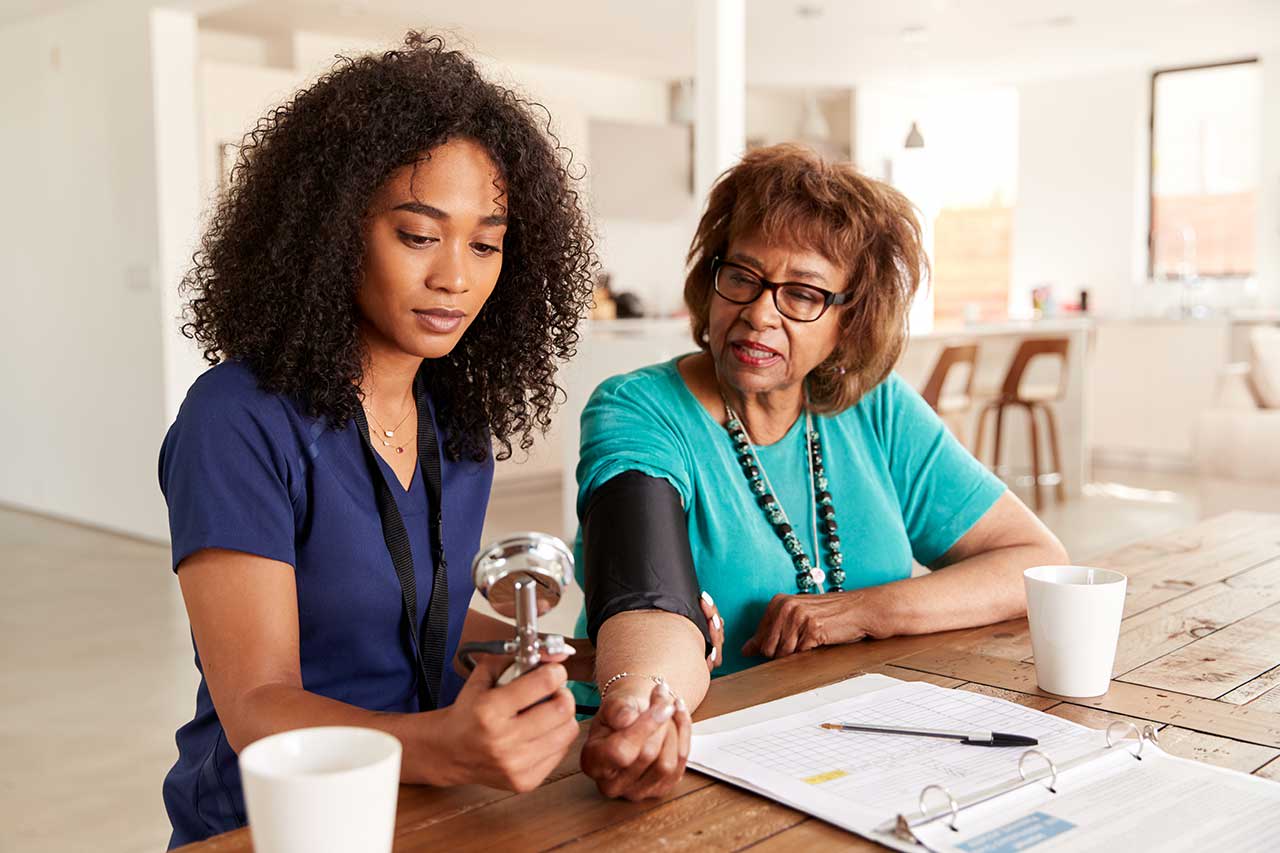 A caregiver taking a resident's blood pressure at a table