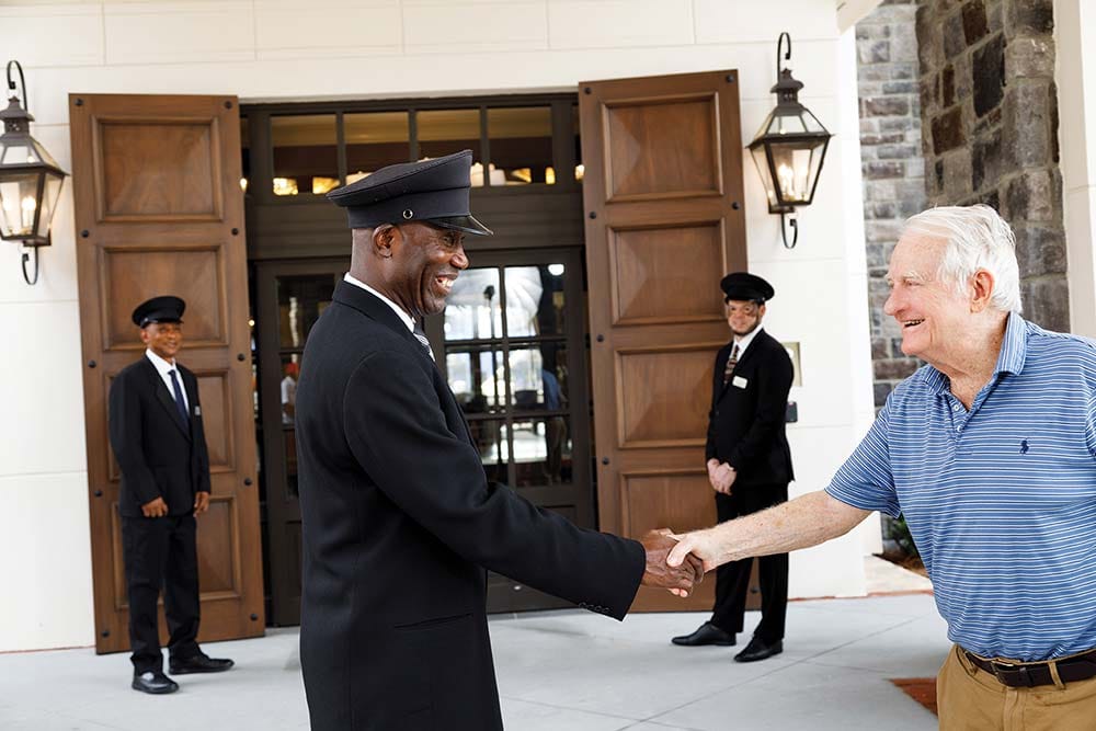 A resident shaking hands with staff outside the facility