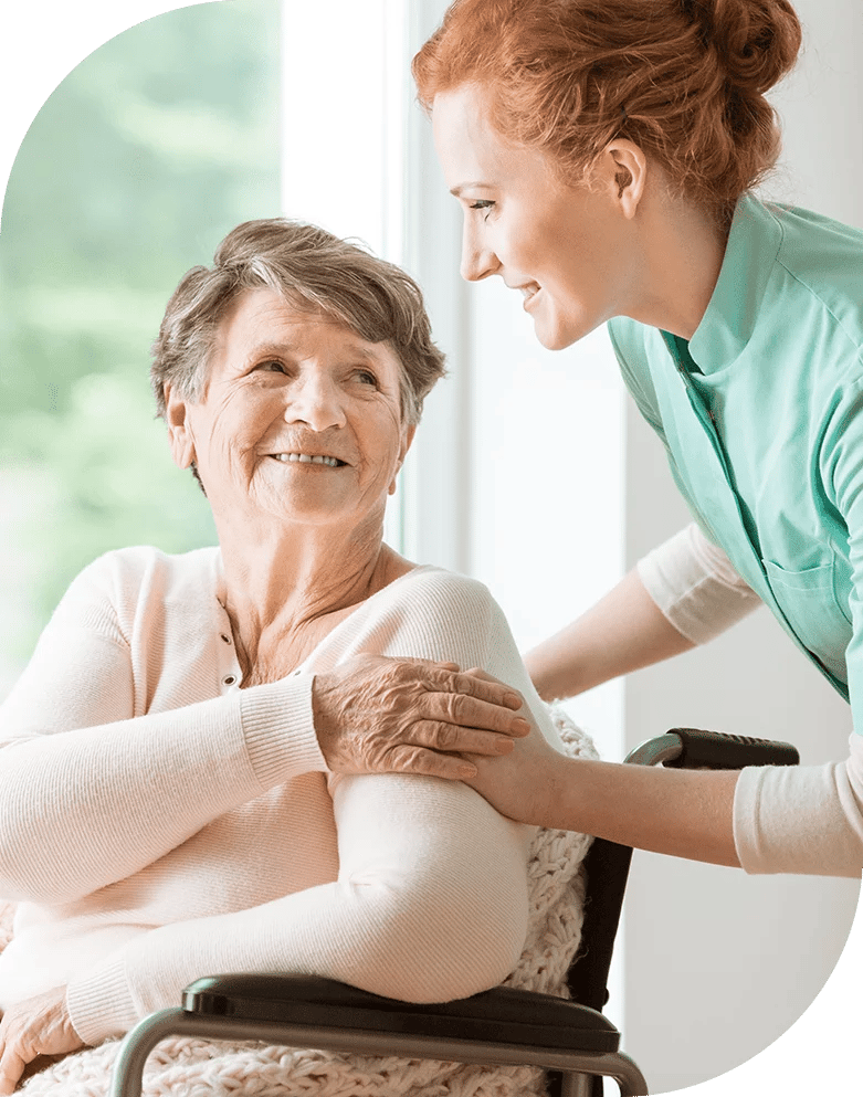 Caregiver assisting a happy resident in a bright room.