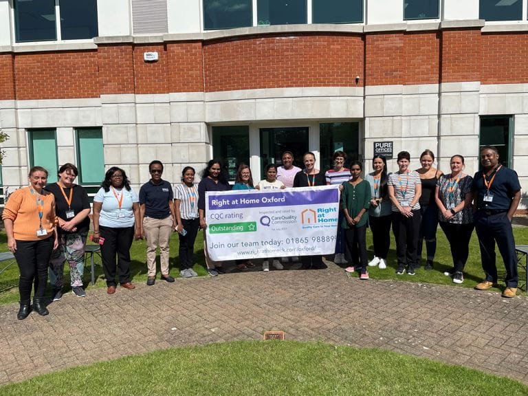 Group of staff members holding a banner outside the facility.