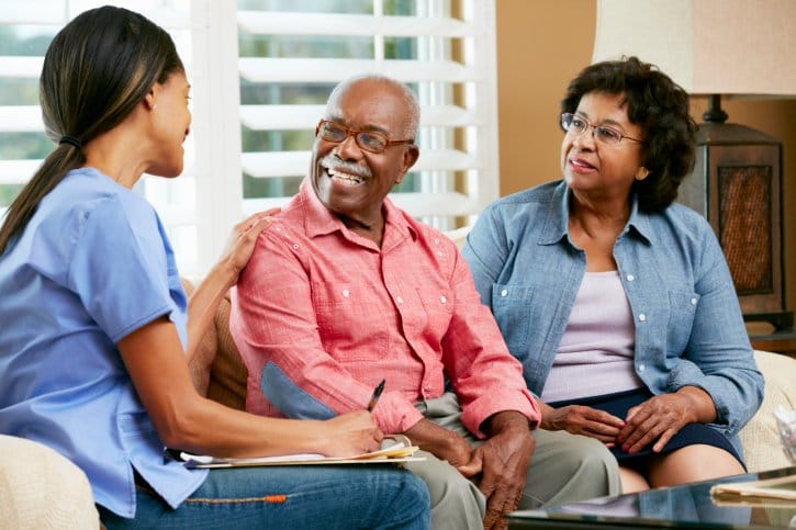 Healthcare worker interacting with elderly couple.