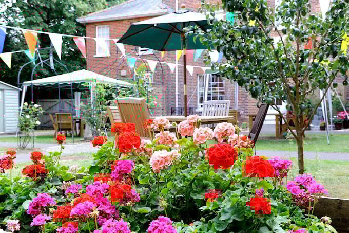Vibrant flowerbeds in the garden with colorful flags in the background.