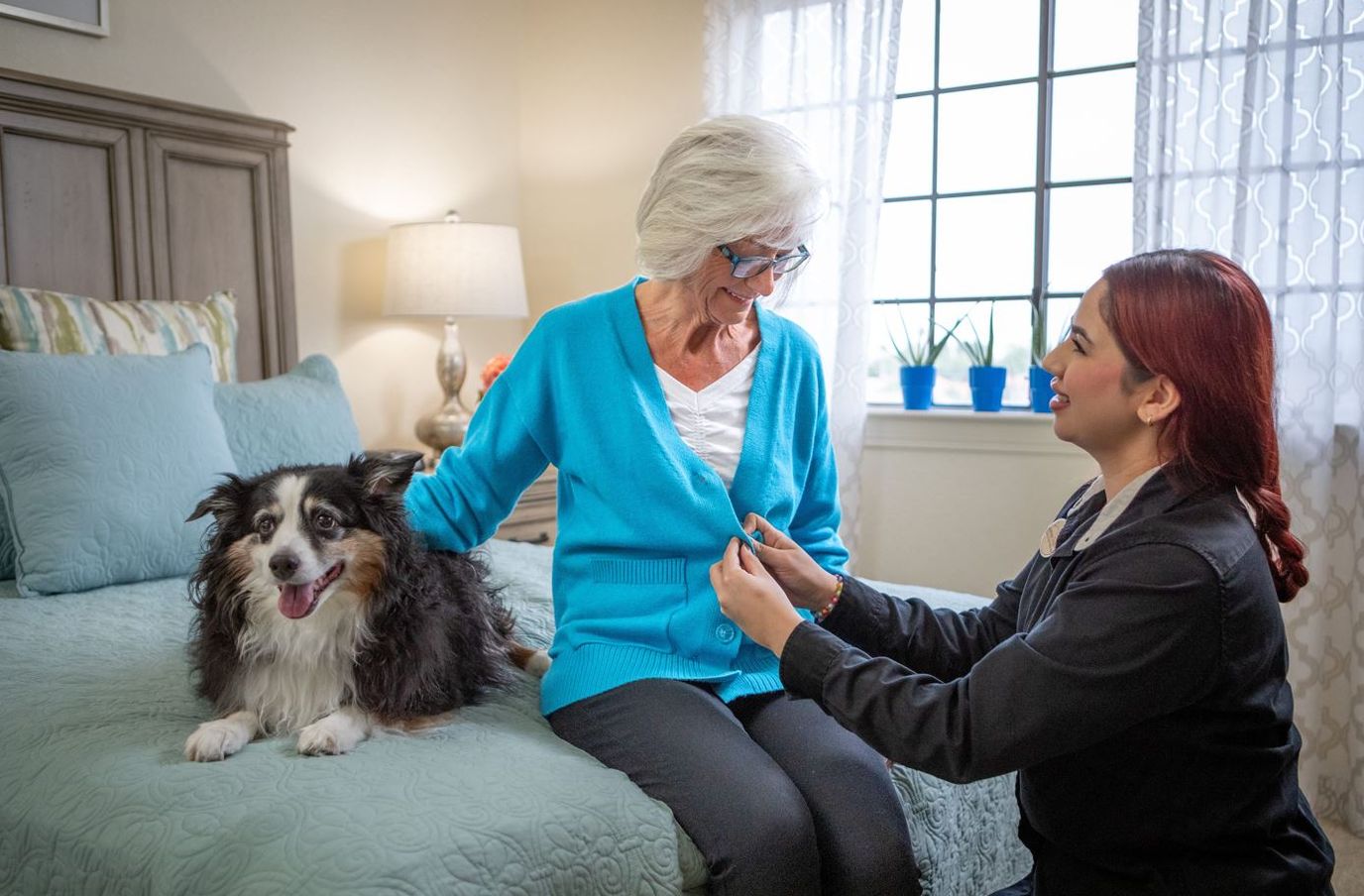 Senior resident interacting with staff and a dog in a cozy room