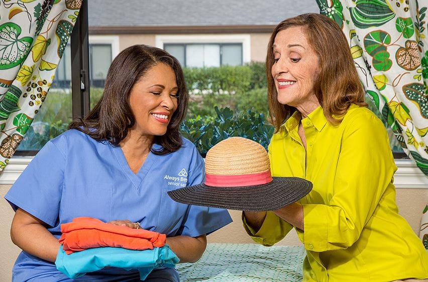 A caregiver and a senior resident discussing a straw hat.