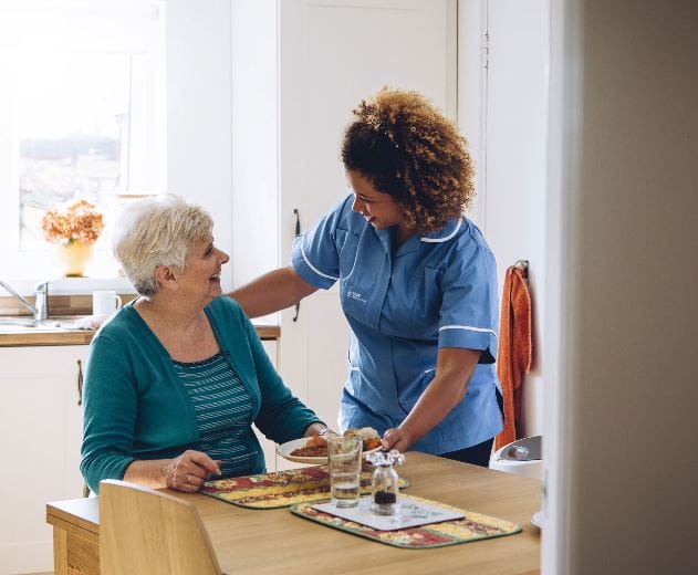 Caregiver assisting a resident in a warm, inviting kitchen