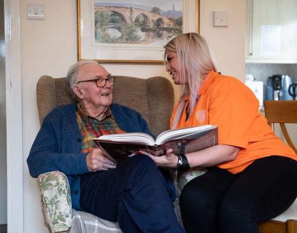 Care staff sharing a book with a resident