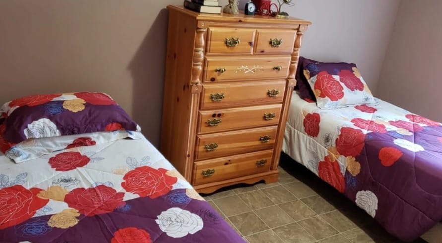 Cozy twin bedroom with floral bedding and wooden dresser
