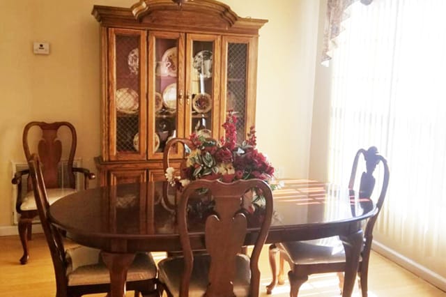 Wooden dining table with floral centerpiece and china cabinet