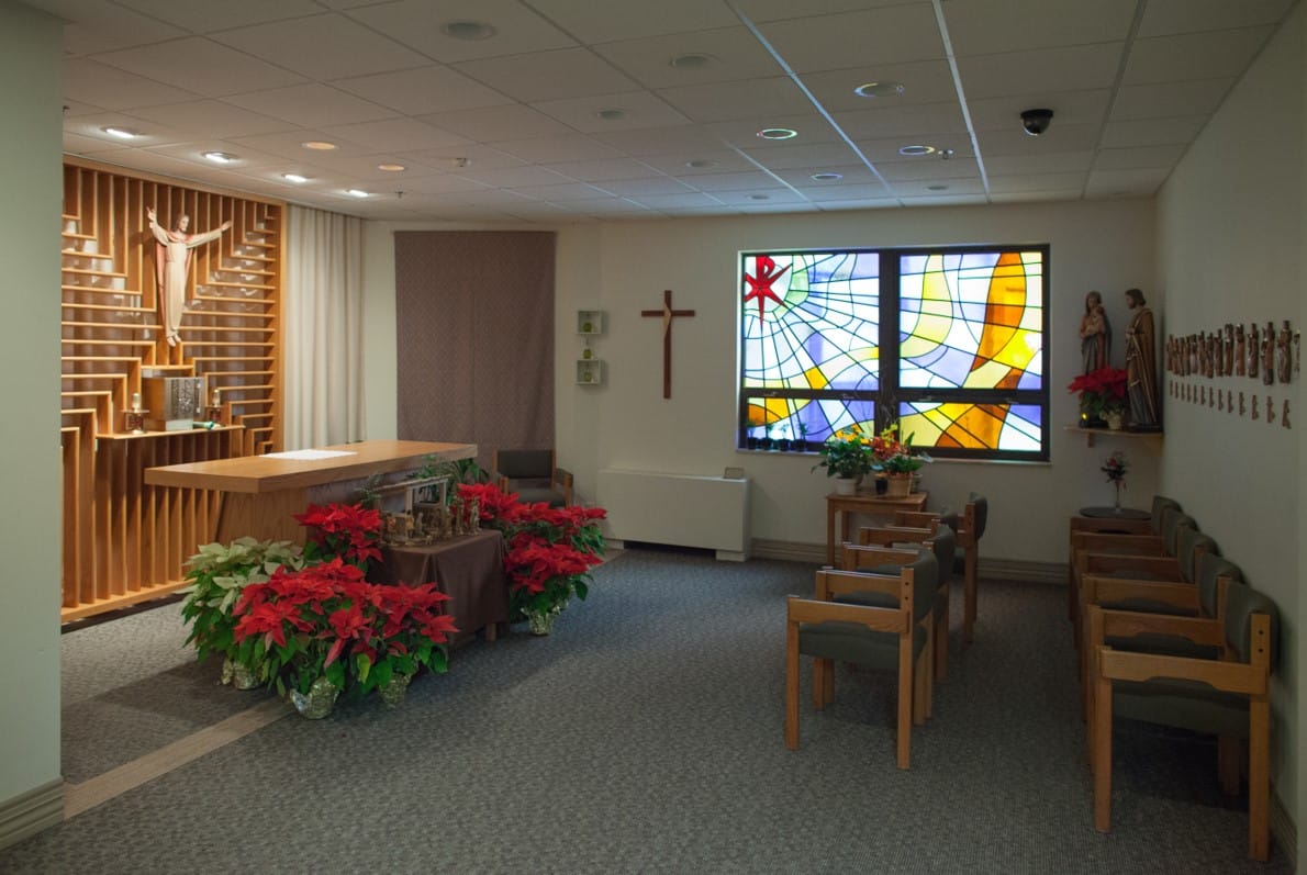 Interior of the chapel with a stained glass window and Christmas poinsettias