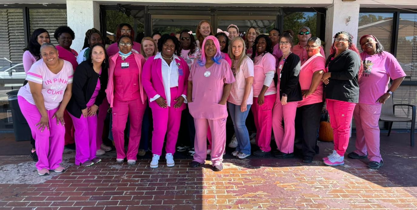 Group of staff in pink attire at the facility entrance