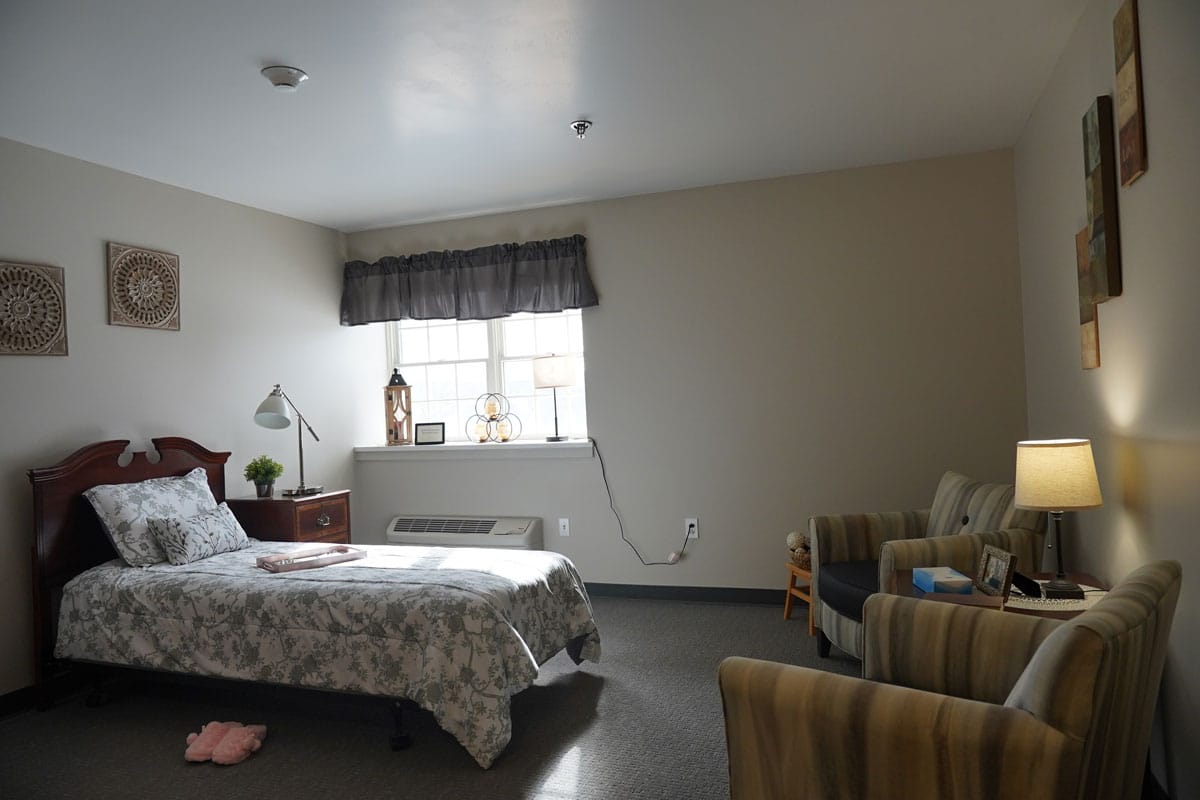 A well-furnished bedroom with a bed, lamp, and seating area.