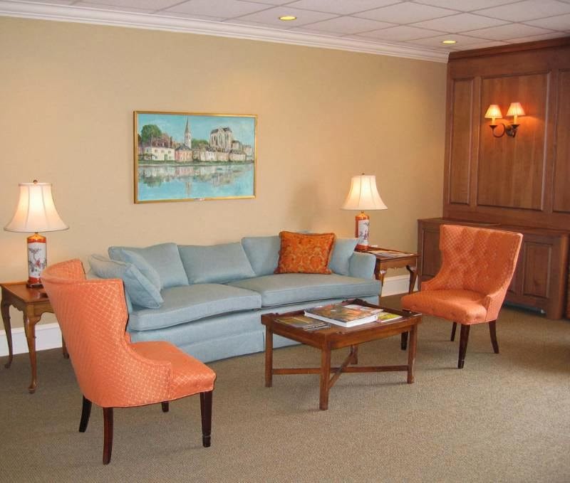 A cozy living room with blue sofa, orange chairs, and a wooden coffee table.