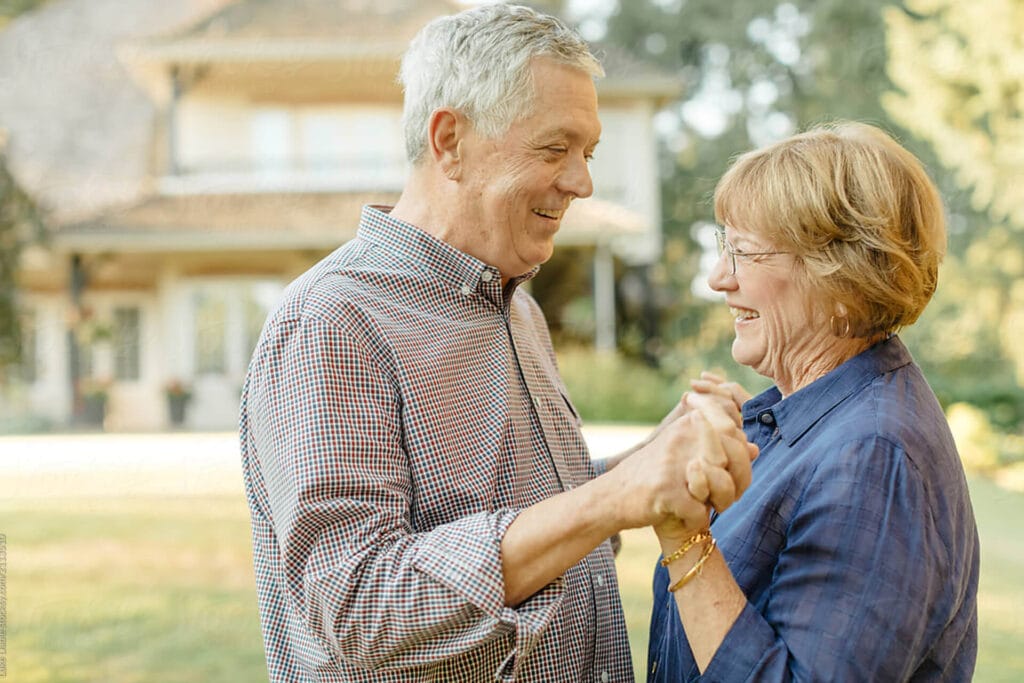 Two seniors dancing happily outside