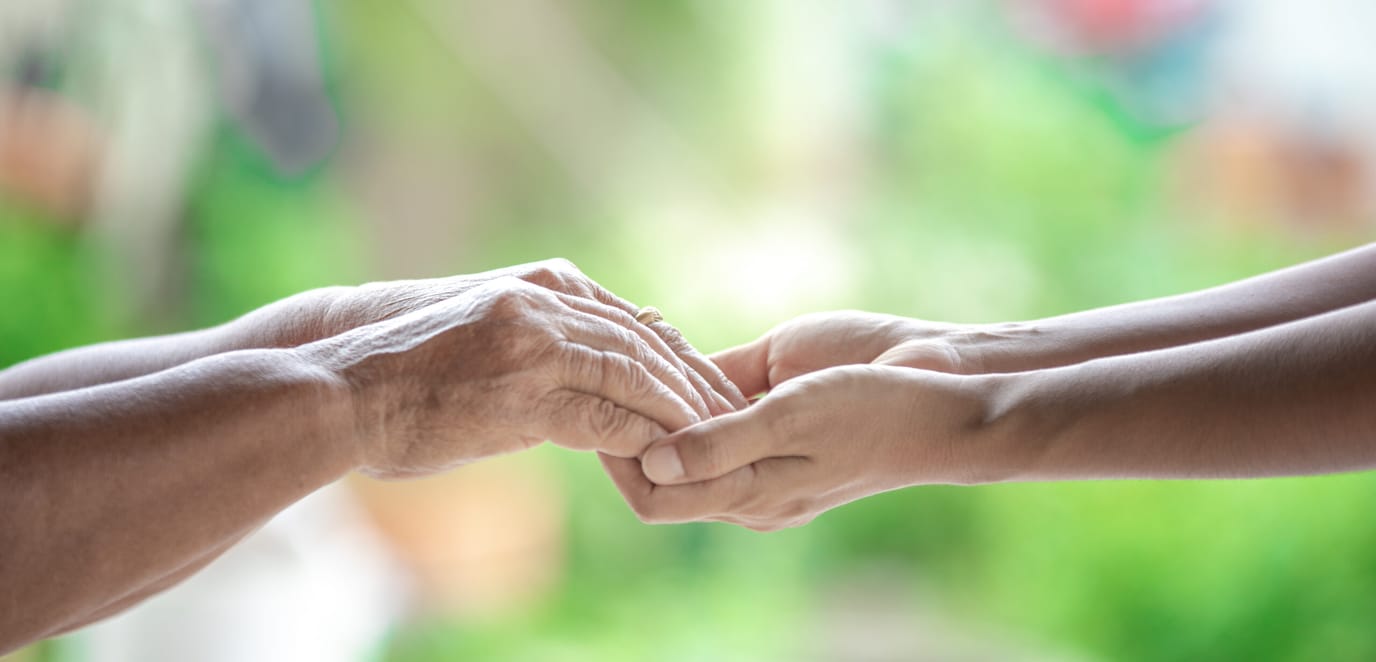 Elderly and younger hands clasped together