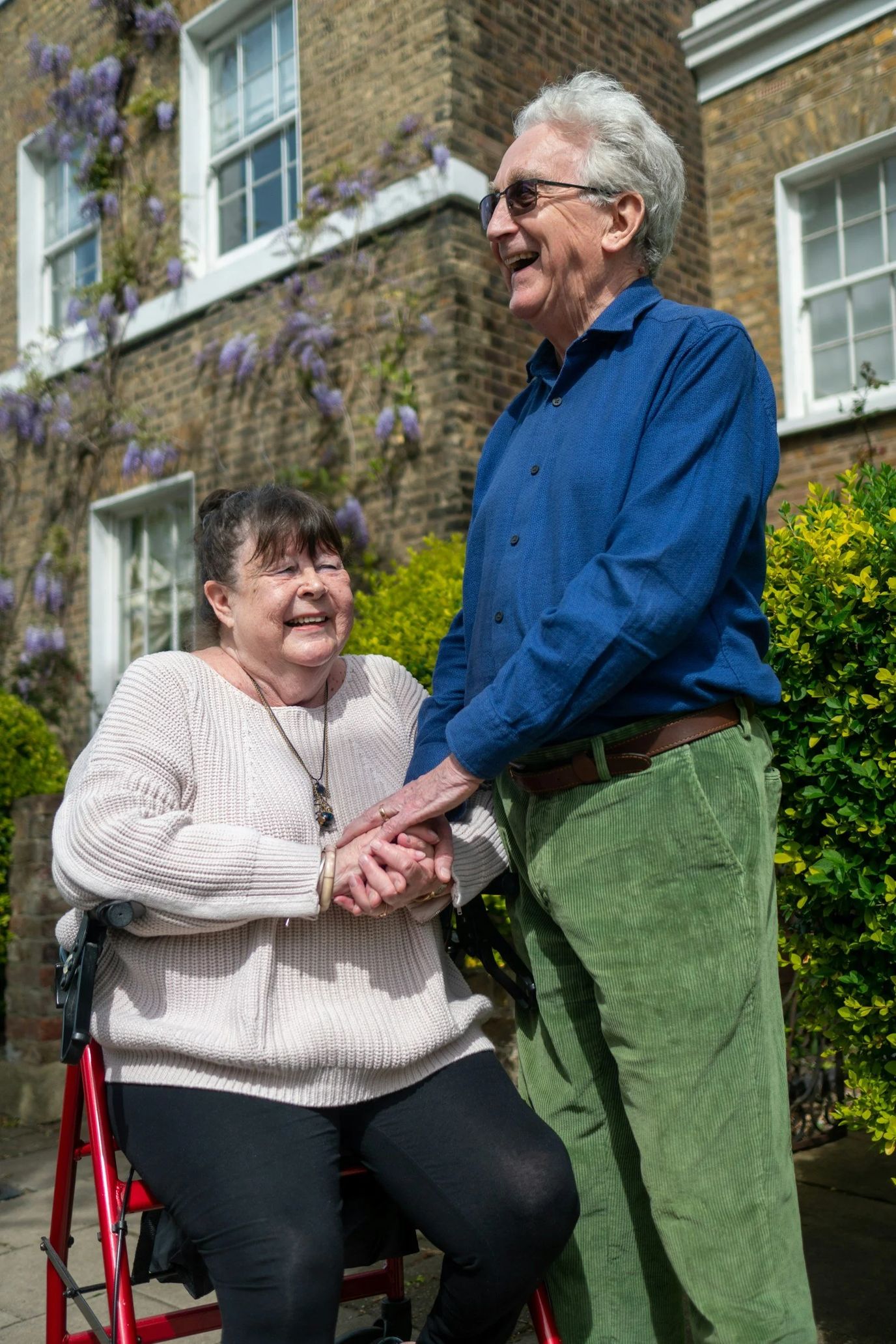 Two smiling seniors in a garden setting.