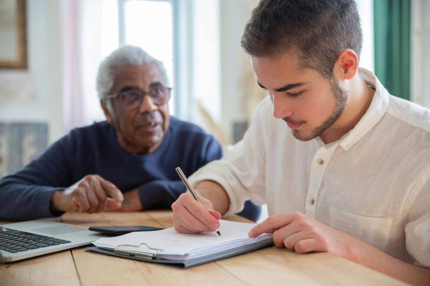 A young man helping an elderly man with paperwork