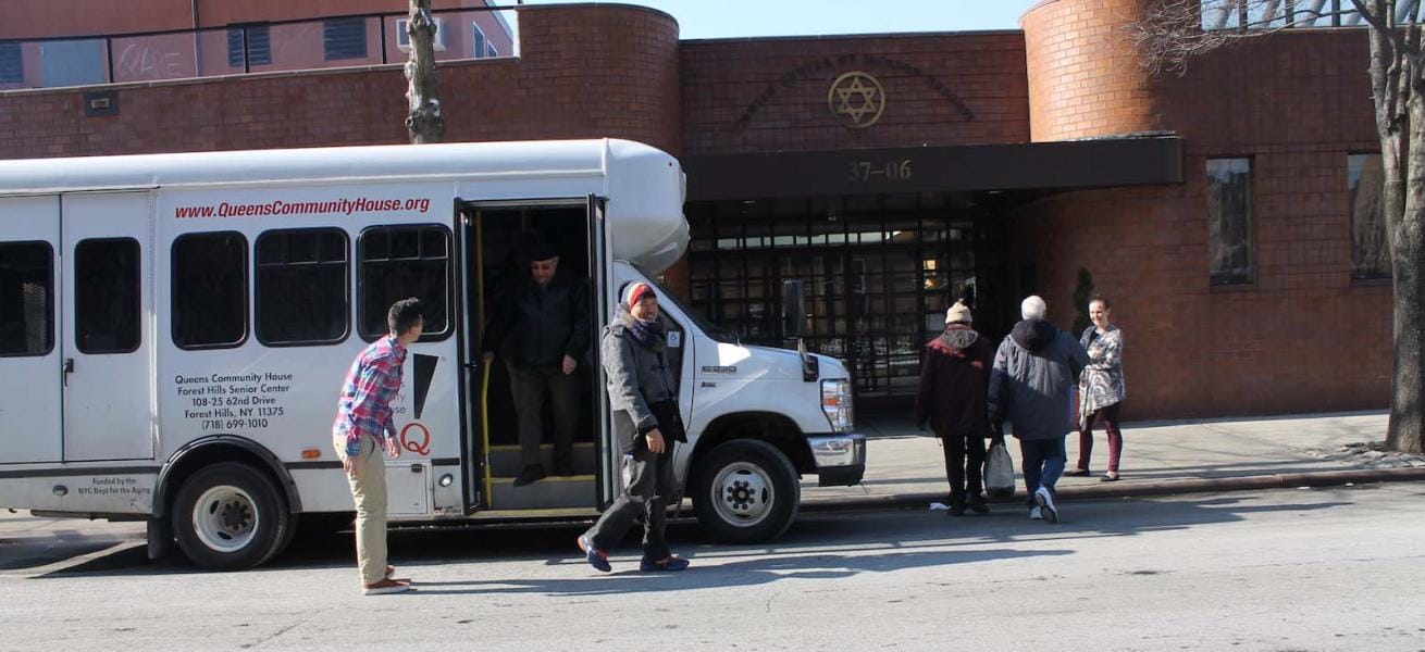 Residents and staff near facility bus outside