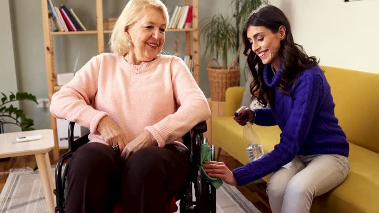Caregiver assisting elderly woman in a cozy living area.