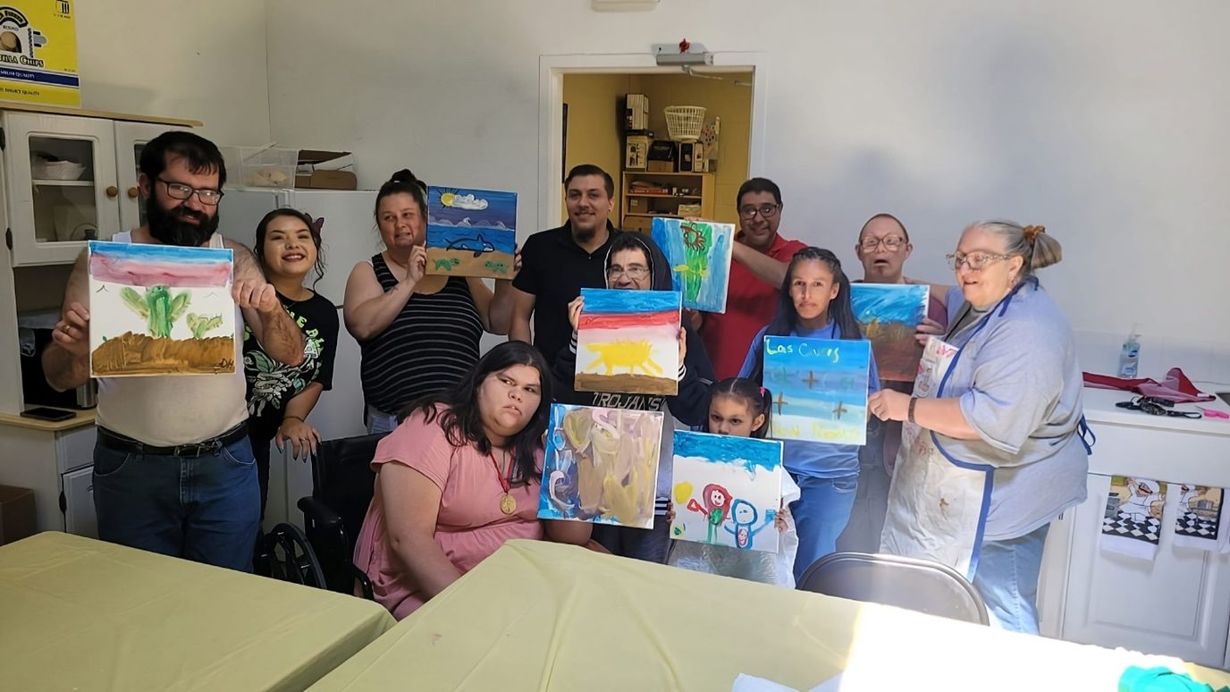 Residents and staff holding up their artwork in a group activity.