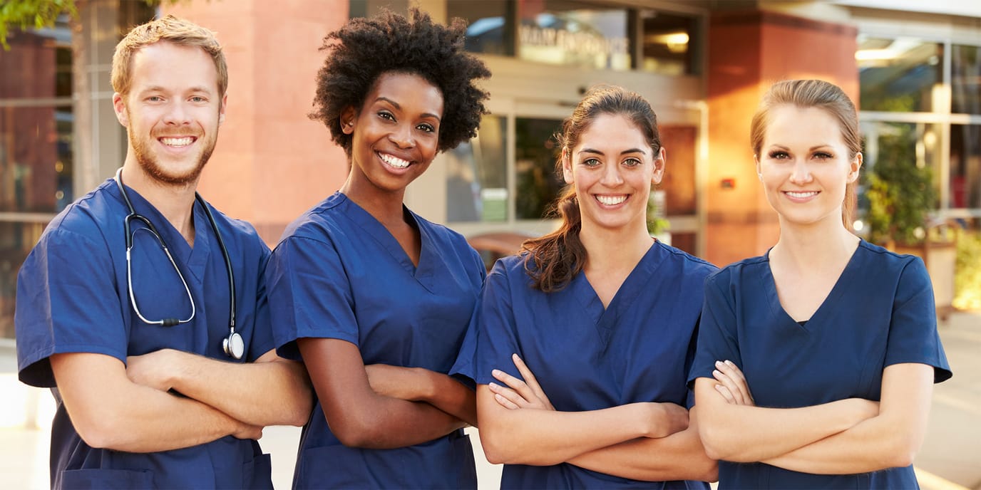 Four smiling healthcare staff in scrubs