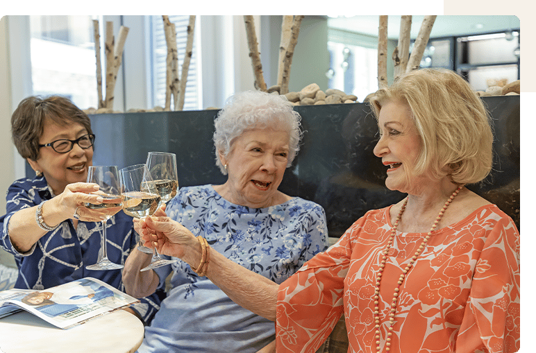 Three residents toasting with glasses at a gathering.