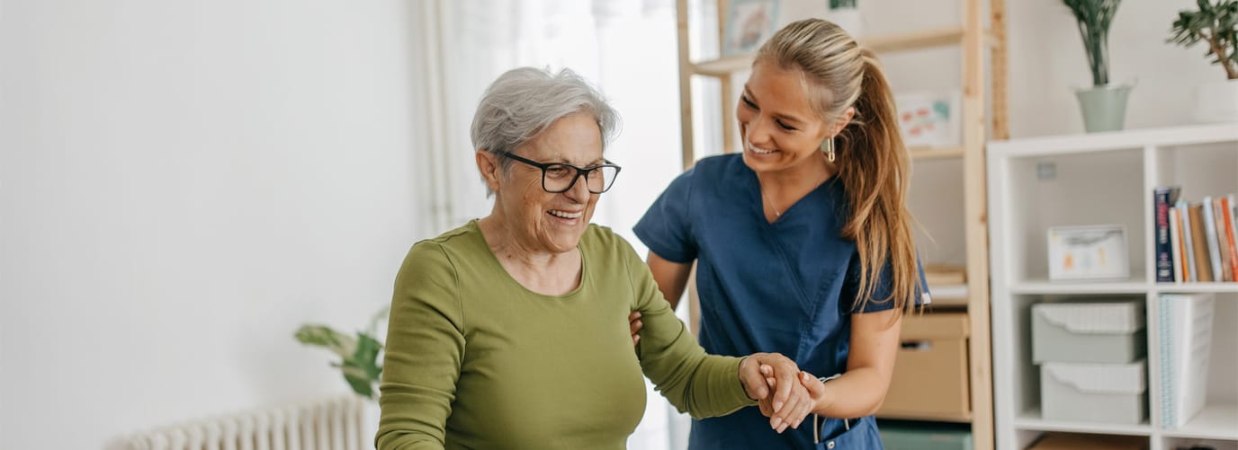Caregiver assisting a senior woman indoors