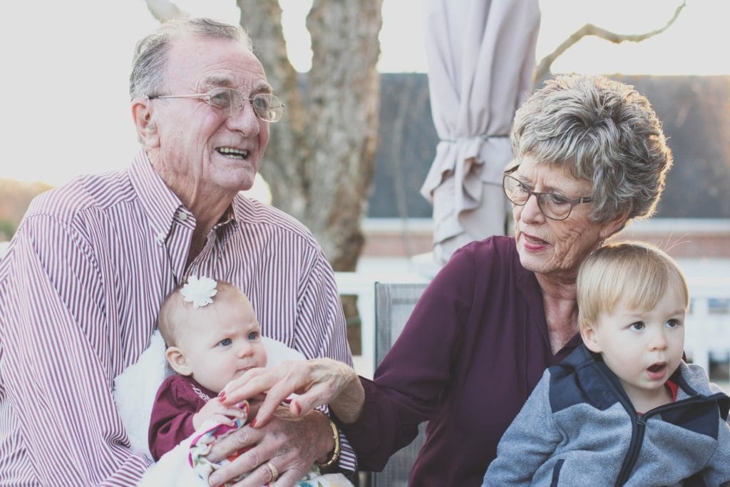Elderly couple enjoying time with young children outdoors