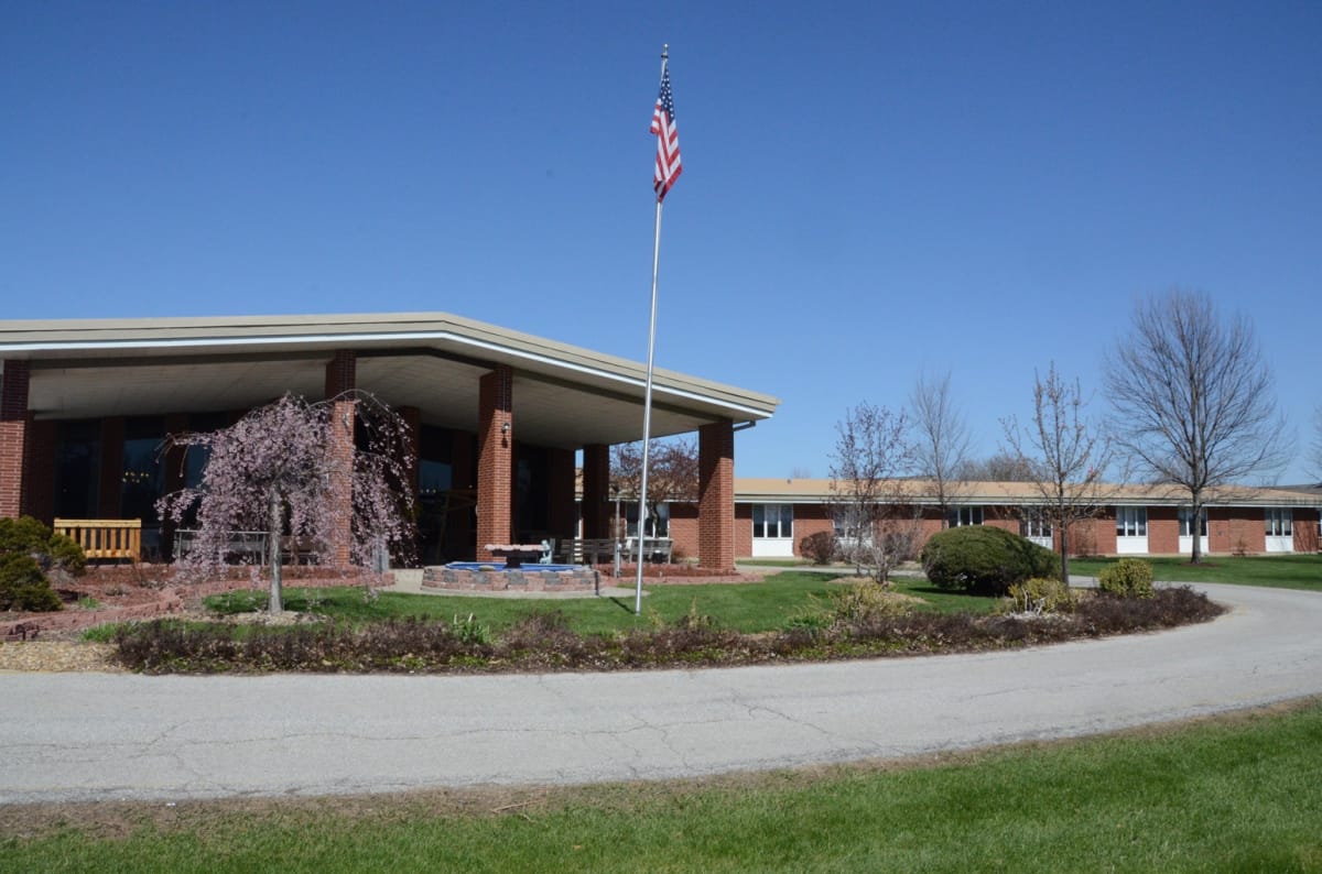 Front view of a senior living facility building with flag