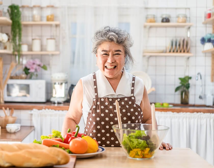 A resident happily preparing food in the kitchen